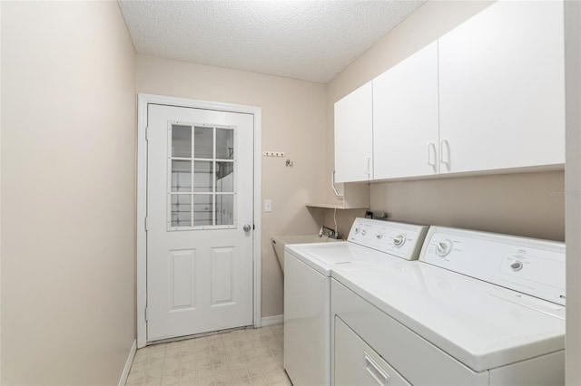 washroom featuring washing machine and clothes dryer, cabinets, and a textured ceiling