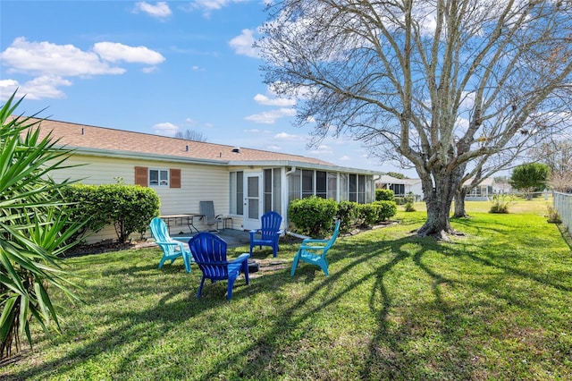 rear view of house featuring a yard and a sunroom