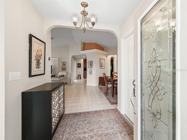 entryway featuring an inviting chandelier, vaulted ceiling, and tile patterned floors