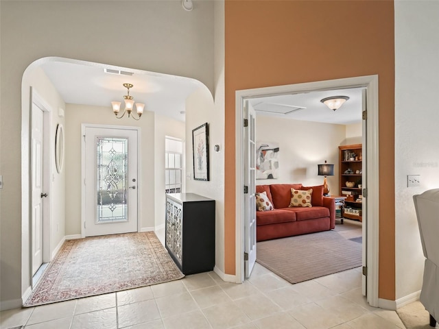 foyer entrance with light tile patterned flooring and an inviting chandelier