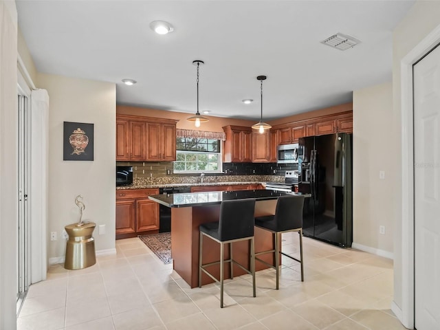 kitchen with tasteful backsplash, dark stone countertops, a kitchen bar, a center island, and stainless steel appliances