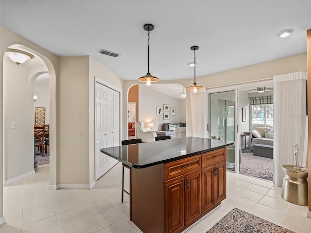 kitchen with a kitchen island, a kitchen breakfast bar, hanging light fixtures, and light tile patterned floors