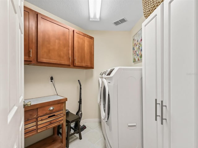 clothes washing area featuring cabinets, light tile patterned flooring, a textured ceiling, and independent washer and dryer