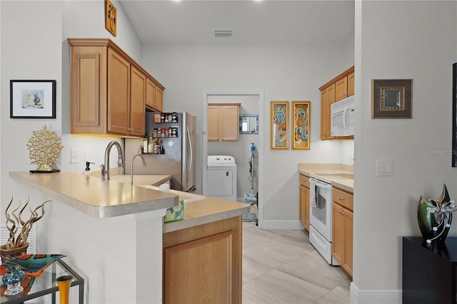 kitchen with washer / dryer, sink, a kitchen breakfast bar, kitchen peninsula, and white appliances