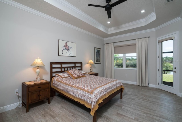 bedroom featuring crown molding, a tray ceiling, light hardwood / wood-style floors, a textured ceiling, and access to outside
