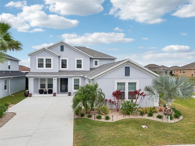 traditional home featuring a front yard, stucco siding, and concrete driveway