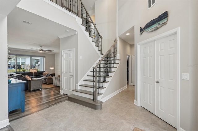 entryway featuring a high ceiling, stairs, baseboards, and visible vents