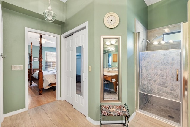 interior space with ceiling fan, vanity, and a shower with door