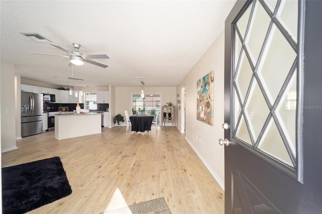 entryway featuring ceiling fan, a textured ceiling, and light hardwood / wood-style floors