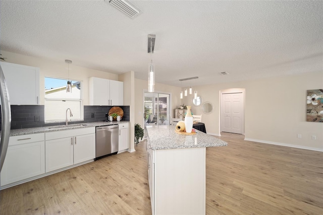 kitchen featuring sink, decorative light fixtures, a center island, stainless steel dishwasher, and white cabinets