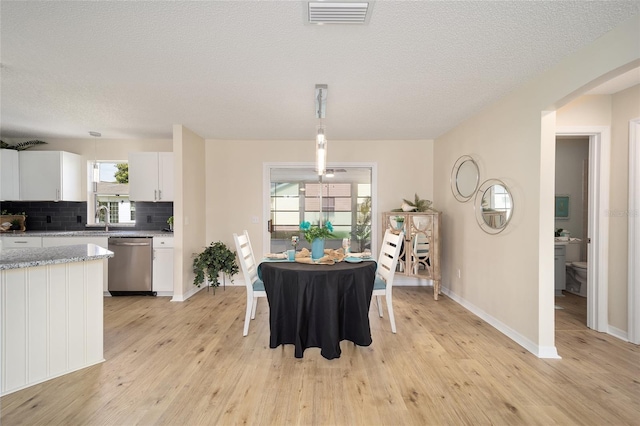 dining space with sink, light hardwood / wood-style flooring, and a textured ceiling
