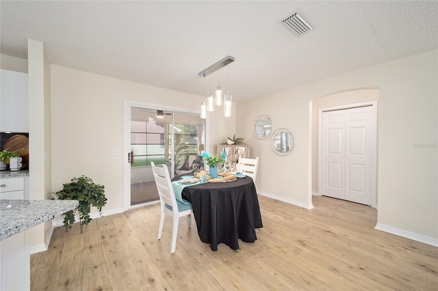 dining area with light hardwood / wood-style floors and a textured ceiling