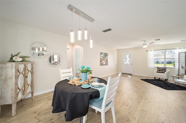 dining room featuring ceiling fan, light hardwood / wood-style floors, and a textured ceiling