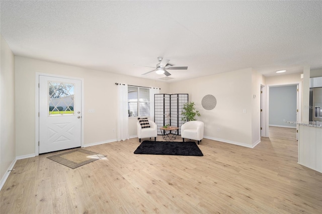 sitting room with ceiling fan, a textured ceiling, and light wood-type flooring