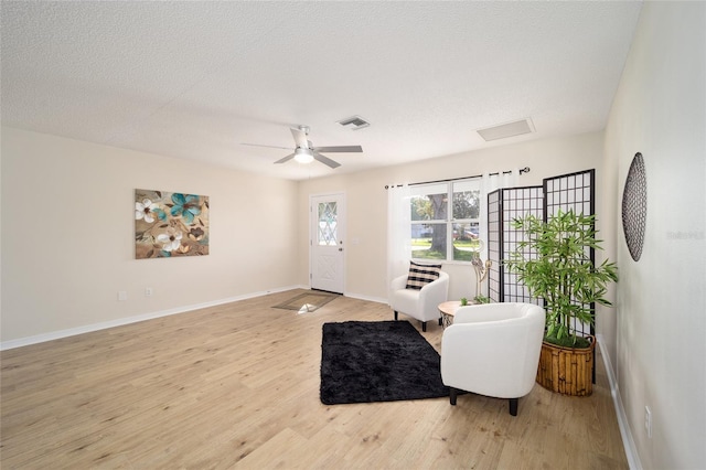 sitting room featuring ceiling fan, light hardwood / wood-style flooring, and a textured ceiling