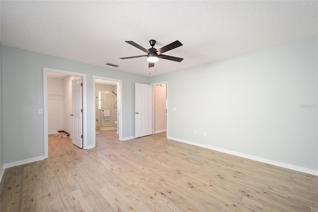 unfurnished bedroom with a spacious closet, light hardwood / wood-style flooring, a closet, and a textured ceiling