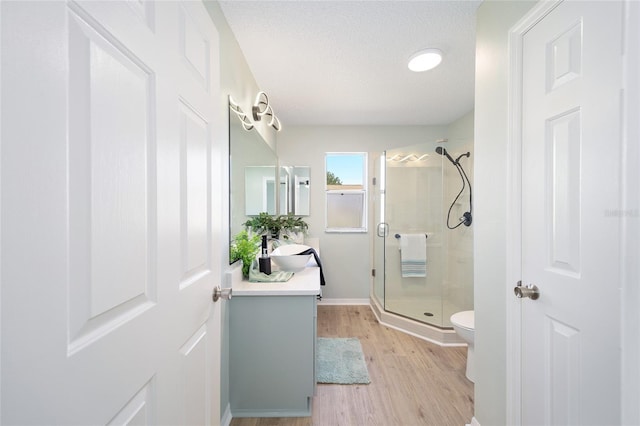 bathroom featuring hardwood / wood-style floors, vanity, an enclosed shower, a textured ceiling, and toilet