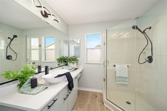 bathroom featuring hardwood / wood-style flooring, vanity, a shower with door, and a textured ceiling
