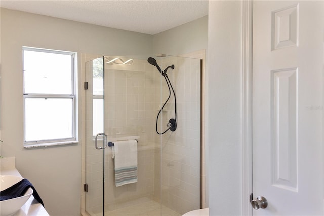 bathroom featuring a shower with shower door and a textured ceiling