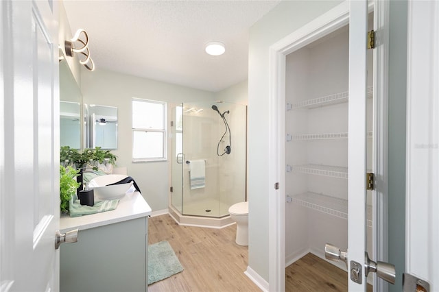 bathroom featuring toilet, a textured ceiling, vanity, a shower with door, and hardwood / wood-style flooring
