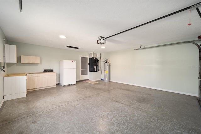 garage featuring water heater, white fridge, and a garage door opener