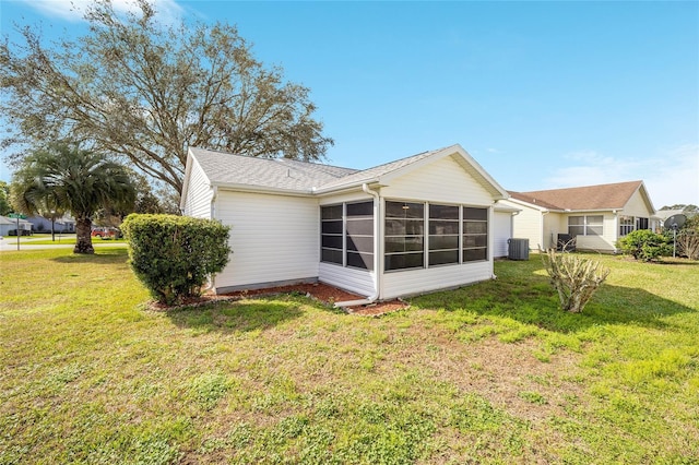 rear view of property with a yard, a sunroom, and central air condition unit