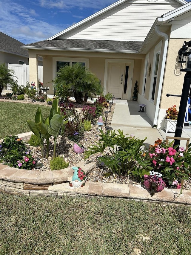 6576 Merrill Ln, The Villages, FL 34762 - view of exterior entry with a shingled roof, fence, and stucco siding