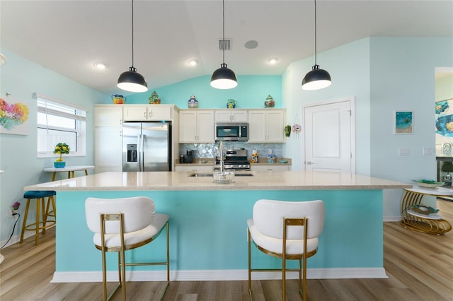6576 Merrill Ln, The Villages, FL 34762 - kitchen featuring white cabinets, tasteful backsplash, appliances with stainless steel finishes, a sink, and light wood-type flooring