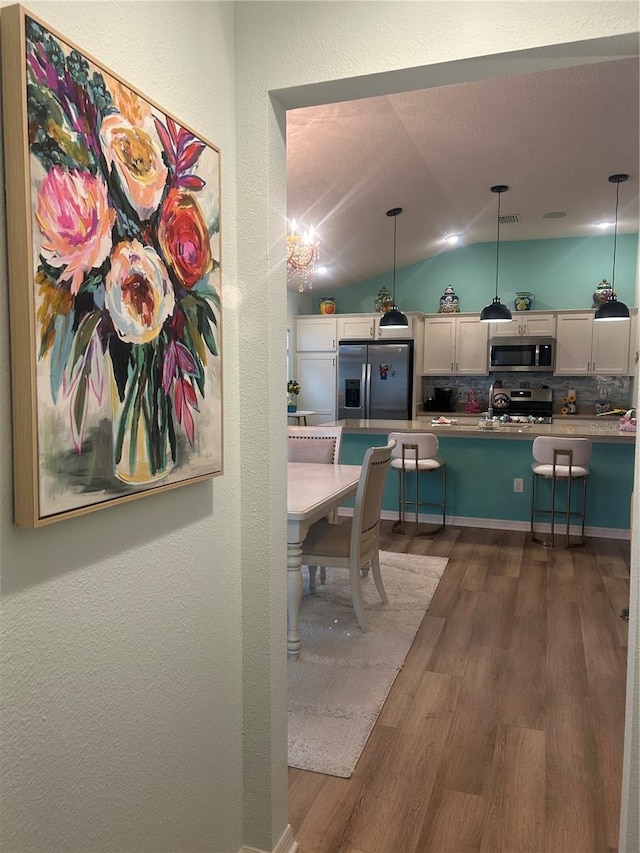 6576 Merrill Ln, The Villages, FL 34762 - dining area with vaulted ceiling, a textured ceiling, dark wood finished floors, visible vents, and a textured wall