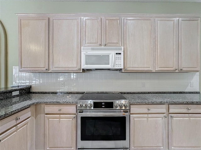 kitchen with electric stove, backsplash, dark stone counters, and light brown cabinets