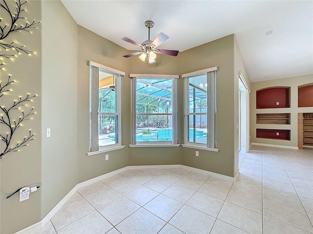 unfurnished room with a healthy amount of sunlight, light tile patterned floors, and ceiling fan