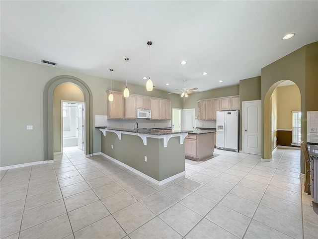 kitchen with light brown cabinetry, hanging light fixtures, light tile patterned floors, kitchen peninsula, and white appliances