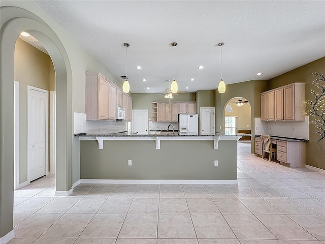 kitchen featuring light tile patterned floors, white appliances, light brown cabinetry, and decorative light fixtures