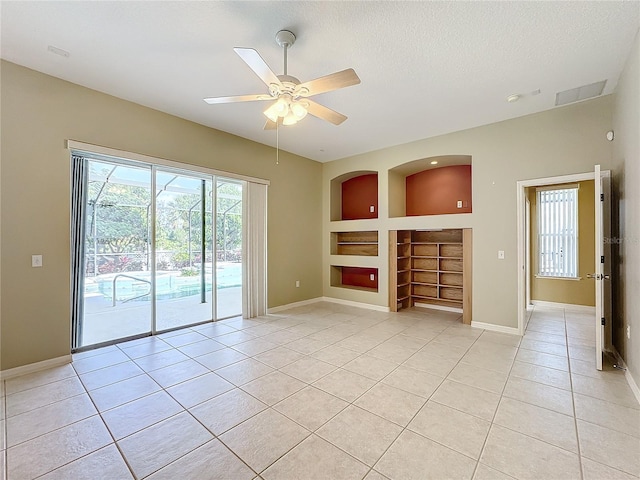 unfurnished living room featuring light tile patterned flooring, ceiling fan, built in features, and a textured ceiling