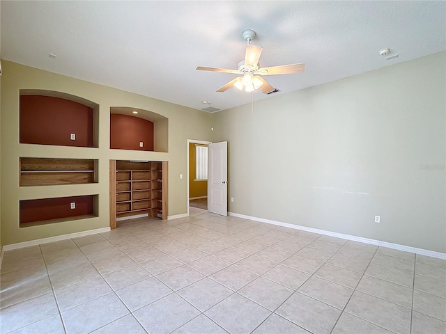 unfurnished living room featuring light tile patterned floors, built in shelves, and ceiling fan