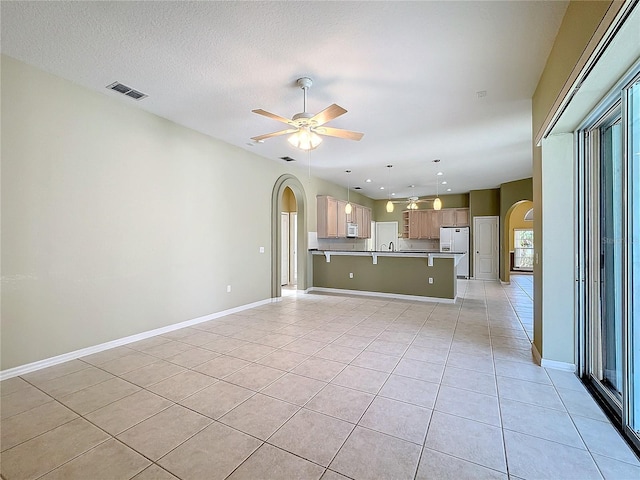 unfurnished living room with ceiling fan, a textured ceiling, and light tile patterned floors