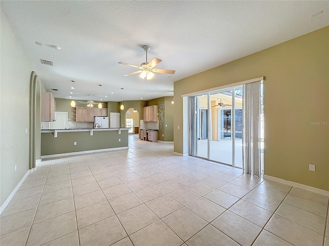 unfurnished living room featuring a textured ceiling, ceiling fan, and light tile patterned flooring