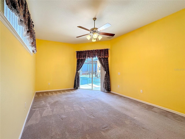 carpeted empty room with ceiling fan and a textured ceiling