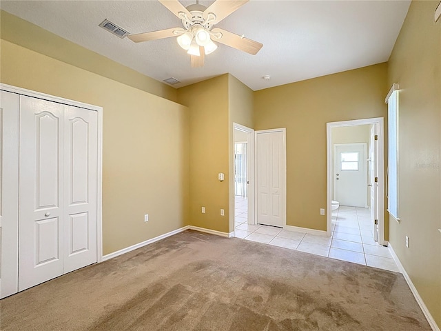 unfurnished bedroom featuring ceiling fan, ensuite bathroom, and light carpet