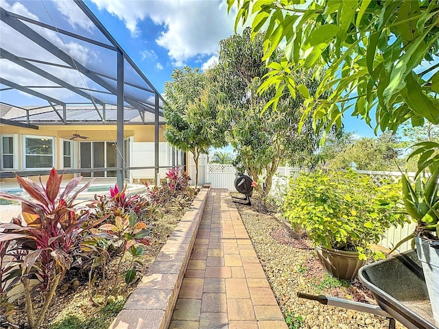 view of yard with a fenced in pool, ceiling fan, and glass enclosure