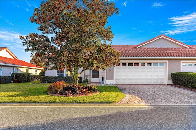 view of front of home featuring a garage, a tile roof, decorative driveway, a front lawn, and stucco siding