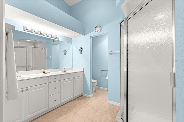 bathroom featuring double vanity, toilet, a stall shower, a sink, and tile patterned floors