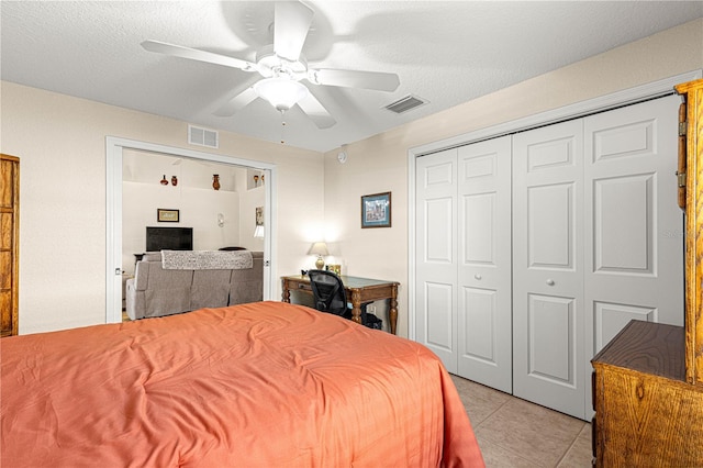 bedroom with a closet, visible vents, light tile patterned flooring, ceiling fan, and a textured ceiling