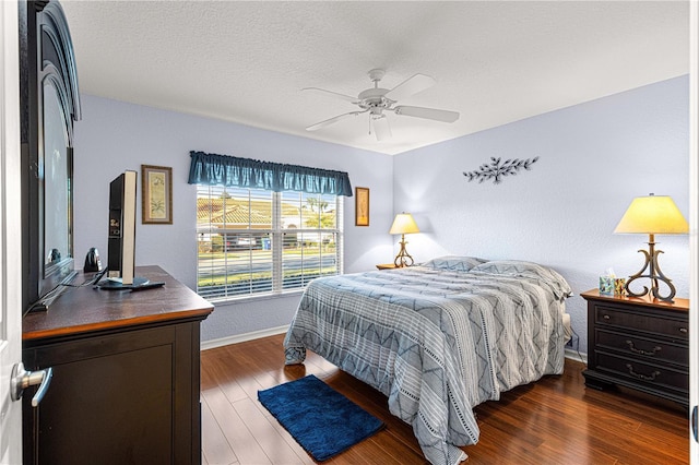 bedroom with a ceiling fan, dark wood-style flooring, a textured ceiling, and baseboards