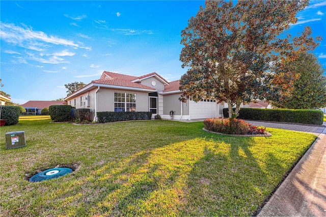 view of front of property with an attached garage, stucco siding, a front yard, and a tiled roof