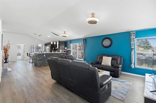 living room with lofted ceiling, baseboards, and wood finished floors