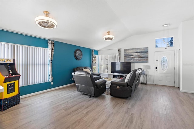 living area featuring vaulted ceiling, baseboards, and wood finished floors