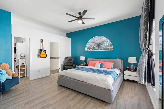 bedroom with a ceiling fan, connected bathroom, baseboards, and wood finished floors