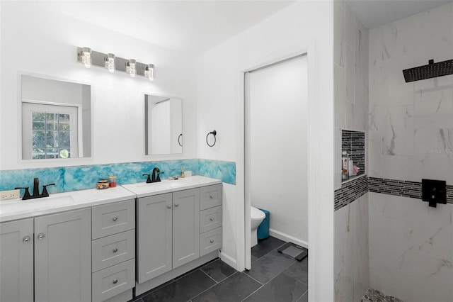 bathroom featuring double vanity, tiled shower, a sink, and toilet