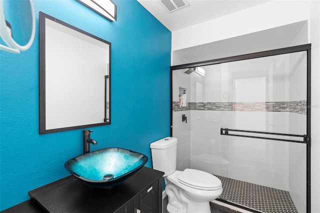 bathroom featuring toilet, a stall shower, visible vents, and vanity